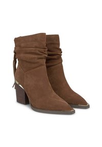 Botas de tobillo de ante marrón con un diseño arrugado, puntas afiladas y tacones de madera gruesos. Presenta un acento metálico en el tacón y un fleco decorativo.