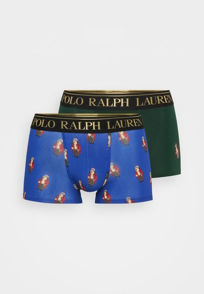 Dois pares de boxers masculinos: um azul com figuras impressas repetidas em casacos vermelhos e verdes, o outro verde sólido com uma cintura preta.