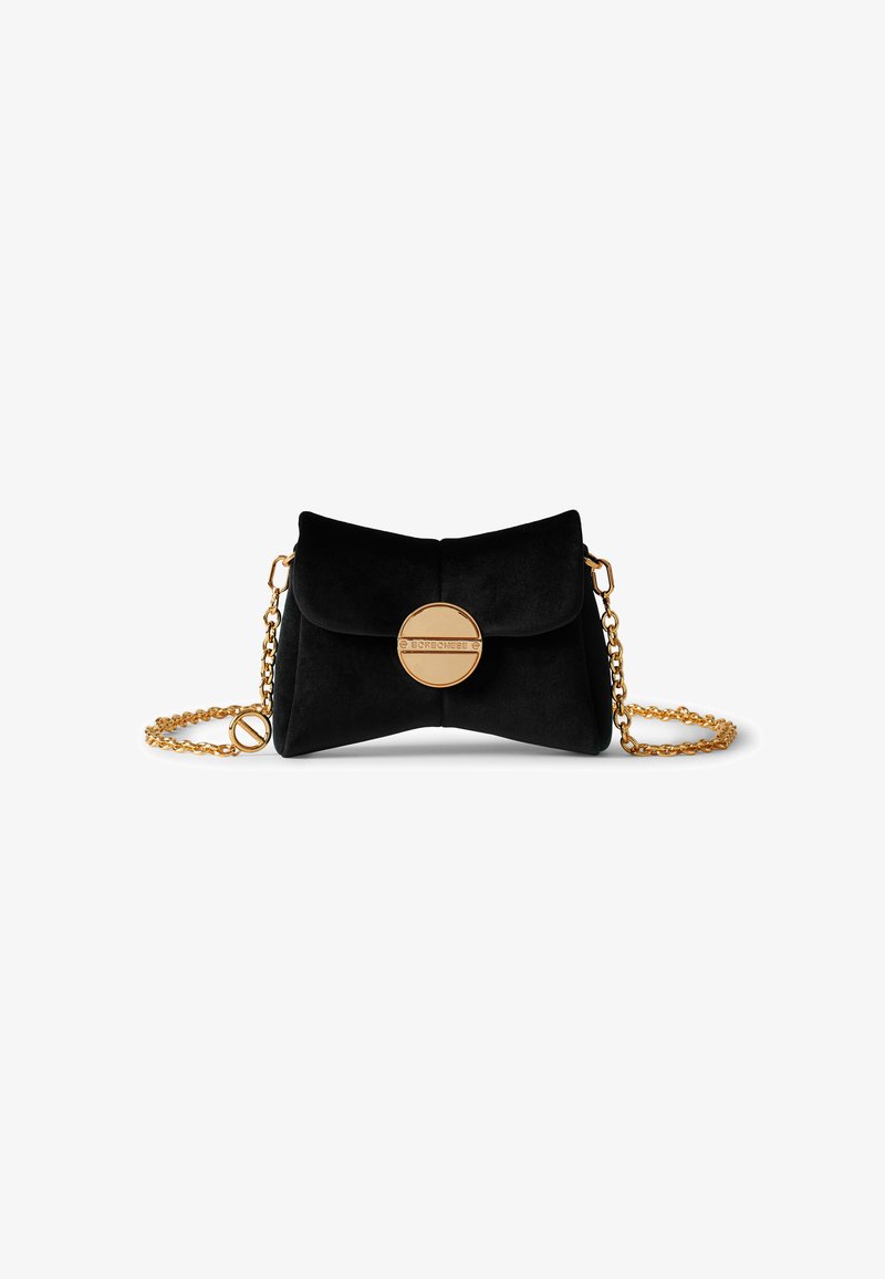 Pochette en suede noir avec un fermoir circulaire en or, une chaîne en bandoulière et un design plié, présentant une texture lisse et peu d'embellissements.