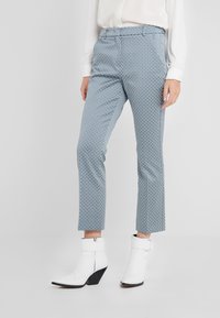 Blauwe en witte gebloemde broek van stof, met een cropped ontwerp, rechte pijpen en een vlakke tailleband, gecombineerd met witte enkellaarsjes.