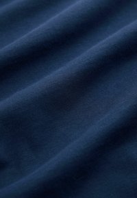 Mørkeblå tekstil med en glat, struktureret overflade, der viser bløde folder og ensartet strikkemønster gennemgående. Holdbart og let materiale.