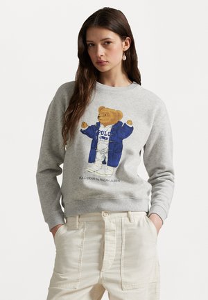 Szara bluza z kapturem z rysunkiem misia w niebieskiej kurtce. Miś jest wyśrodkowany, a poniżej znajduje się napis "POLO BEAR by RALPH LAUREN". Miękka faktura.