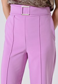 Pantalons lilas taille haute avec des coutures verticales et une ceinture en tissu assortie avec une boucle en argent rectangulaire.