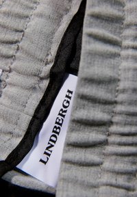 Szürke anyag texturált bordákkal, fekete díszítéssel és jól látható "LINDERSGH" felirattal. Puha, hajtogatható és könnyű kialakítás.
