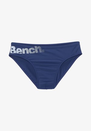 Bas de bikini bleu marine en matériau lisse et extensible. Comprend une large ceinture avec le texte "Bench." imprimé en argent réfléchissant.