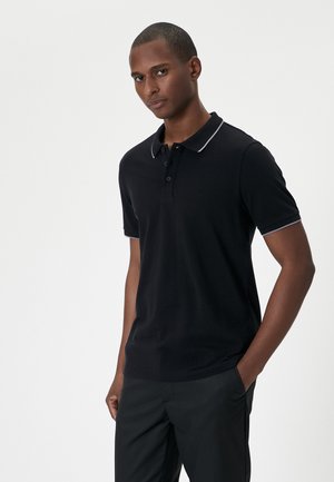 Zwarte poloshirt van katoen met een klassieke kraag, een drie-knopen pat en contrasterend grijs afwerkingsrand op de kraag en mouwen.