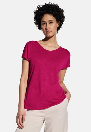 T-shirt fuchsia à manches courtes avec un col rond, fabriqué en tissu doux, offrant une coupe décontractée et une texture lisse. Associé à un pantalon beige.