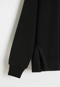 Czarna bluza z długim rękawem, z prążkowanymi mankietami i bocznymi rozcięciami, wykonana z gładkiego materiału o matowym wykończeniu.