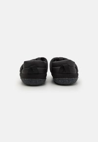 Pantofole nere imbottite con suole testurizzate e cinturini neri regolabili sul retro. Materiale morbido con una forma arrotondata per il comfort.