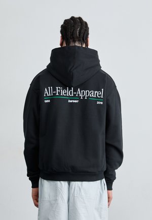 Sort hættetrøje med snøre, med hvid tekst "All-Field-Apparel" og grønne detaljer på ryggen. Lavet af glat, blødt stof.
