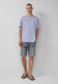 Lichtpaarse katoenen T-shirt, ontspannen pasvorm, ronde halslijn. Gecombineerd met lichtgrijze denim shorts en bruine slidesandalen met een strikaccent.