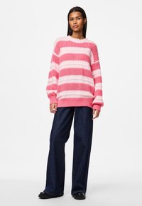 Knit pink and light pink striped sweater with a ribbed neckline and cuffs, paired with dark wide-leg jeans and black shoes.