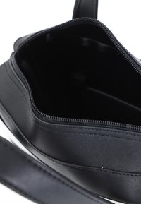 Borsa a tracolla sintetica nera con scomparto interno con zip, texture liscia e tracolla piatta. L'interno presenta un design minimalista.