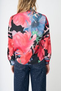 Kukallinen paita, jossa on suuret vaaleanpunaiset ja siniset kukat mustalla pohjalla; yhdistetty tummansinisiin farkkuihin, joissa hopeiset niitit.