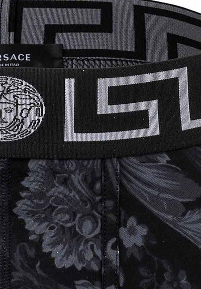 Boxers noirs avec une ceinture texturée grise ornée d'un motif grec en clé et du logo Versace. Motif floral sur le tissu du corps.