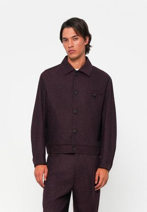 Burgundy jacket made of textured fabric, featuring a collar, front buttons, and a chest pocket with a flap. Long sleeves and straight fit.