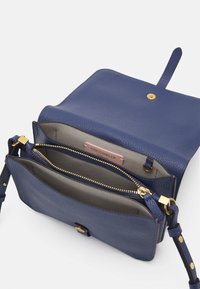 Borsa a tracolla in pelle blu con finitura testurizzata, caratterizzata da due scomparti con cerniera e una chiusura a scatto color oro. Interno con etichetta con il nome del marchio.