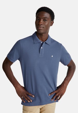 Polo shirt blu navy con maniche corte, colletto e un piccolo logo ricamato sul lato sinistro del petto, indossato da un modello maschile.
