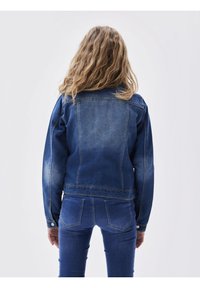 Džínová bunda v tmavě modré barvě, se přiléhavým designem, mírně opotřebenou strukturou a tradičními knoflíkovými manžetami. Zobrazeno zezadu.