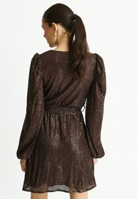 Brown sequin dress with long puff sleeves, a cinched waist, and a flared skirt. The material has a shiny, textured finish.