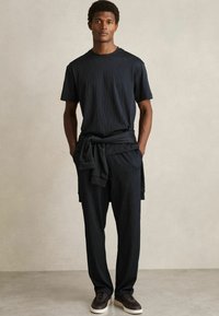 Zwart textuur tweedelig outfit bestaat uit een shirt met korte mouwen en losse broek. Bevat een gestrikt onderdeel in de taille en donkere schoenen.