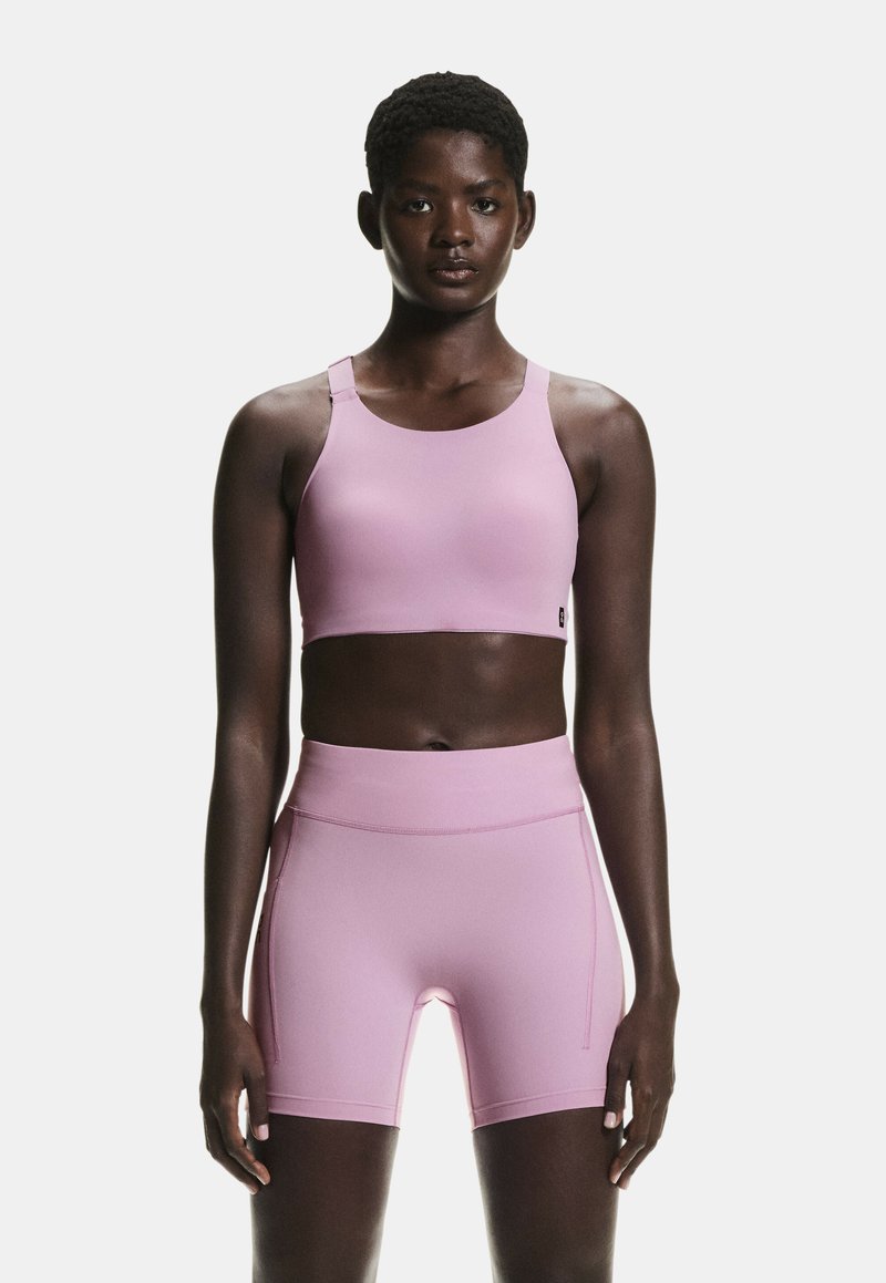 Top sport roz roz și pantaloni scurți cu talie înaltă asortați, confecționați dintr-un material neted și elastic, având un design simplu și cusături minimale.