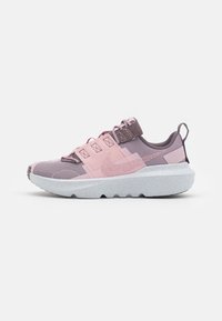 Zapatilla deportiva en tonos morados y rosas con un diseño de malla texturizada, correas reforzadas y una gruesa suela blanca moteada con un patrón de olas.