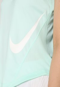 Menta zöld sportfelső, könnyű anyagból készült, fehér Nike swoosh logóval és texturált oldalsó panel részletekkel.