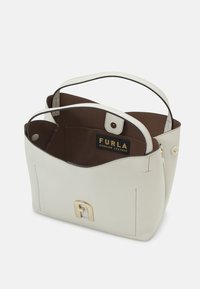 Vit läder tote-väska med texturerad yta, inredningen har brunt foder, detaljer i guldton och en logoplåt. Kort handtag ingår.