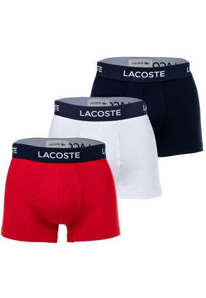 Drie paar boxershorts in rood, wit en marineblauw, elk met een contrasterende marineblauwe tailleband met het "Lacoste" logo.