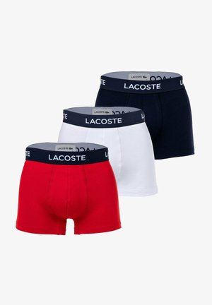 Tre paia di boxer in rosso, bianco e blu navy, ciascuno con un elastico a contrasto blu navy con il logo "Lacoste".