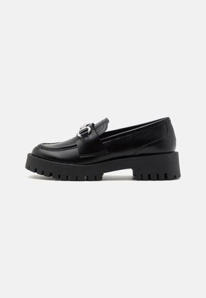 Black leather loafers with a chunky, ridged sole and a metallic buckle accent on the strap. Smooth texture, classic design.
