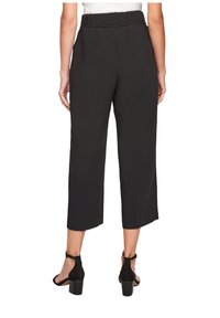 Zwarte cropped broeken met een elastische tailleband, voorzien van een zachte textuur en een iets losse pasvorm, gecombineerd met zwarte haksandalen.