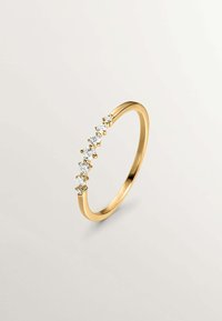 Anillo de oro con una banda curvada y seis piedras transparentes de corte redondo engastadas en garras de oro. Acabado suave, diseño minimalista.