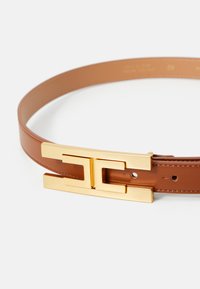 Brown leather belt with a large gold-tone rectangular buckle featuring an interlocking geometric design, displayed on a white background.