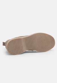 Pantof brown din suede, cu o talpă din cauciuc texturat, având striații verticale și mici orificii de drenaj, conceput pentru aderență și confort.