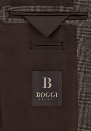 Ruskea kangas, jossa on kuviollinen tekstuuri; sisältää harmaan etiketin, jossa on logo ja "BOGGI MILANO" -teksti; mukana tasku ja yksityiskohtia.