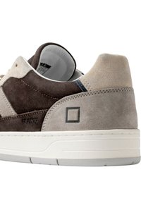 Baskets en daim marron et gris avec semelle blanche, arborant un logo géométrique, des panneaux contrastants et des coutures détaillées sur les côtés.