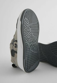 Gray sneaker with black cartoon design on the side. Features textured rubber outsole with herringbone and dot patterns. Lightweight design.