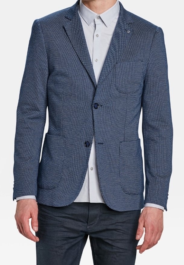 Blå strukturerad kavaj med två framfickor och en knappstängning. Bärs över en ljusgrå skjorta med skräddarsydd passform.