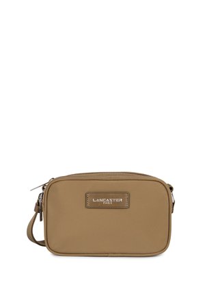 Tan rechthoekige schoudertas gemaakt van synthetisch materiaal. Voorzien van een ritssluiting en een label aan de voorkant met "LANCASTER PARIS" in zilver gedrukt.