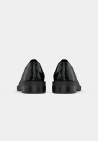 Chaussures en cuir noir avec une finition lisse, bout rond et semelle en caoutchouc épaisse. Présente une couture minimale et un design de talon subtil.