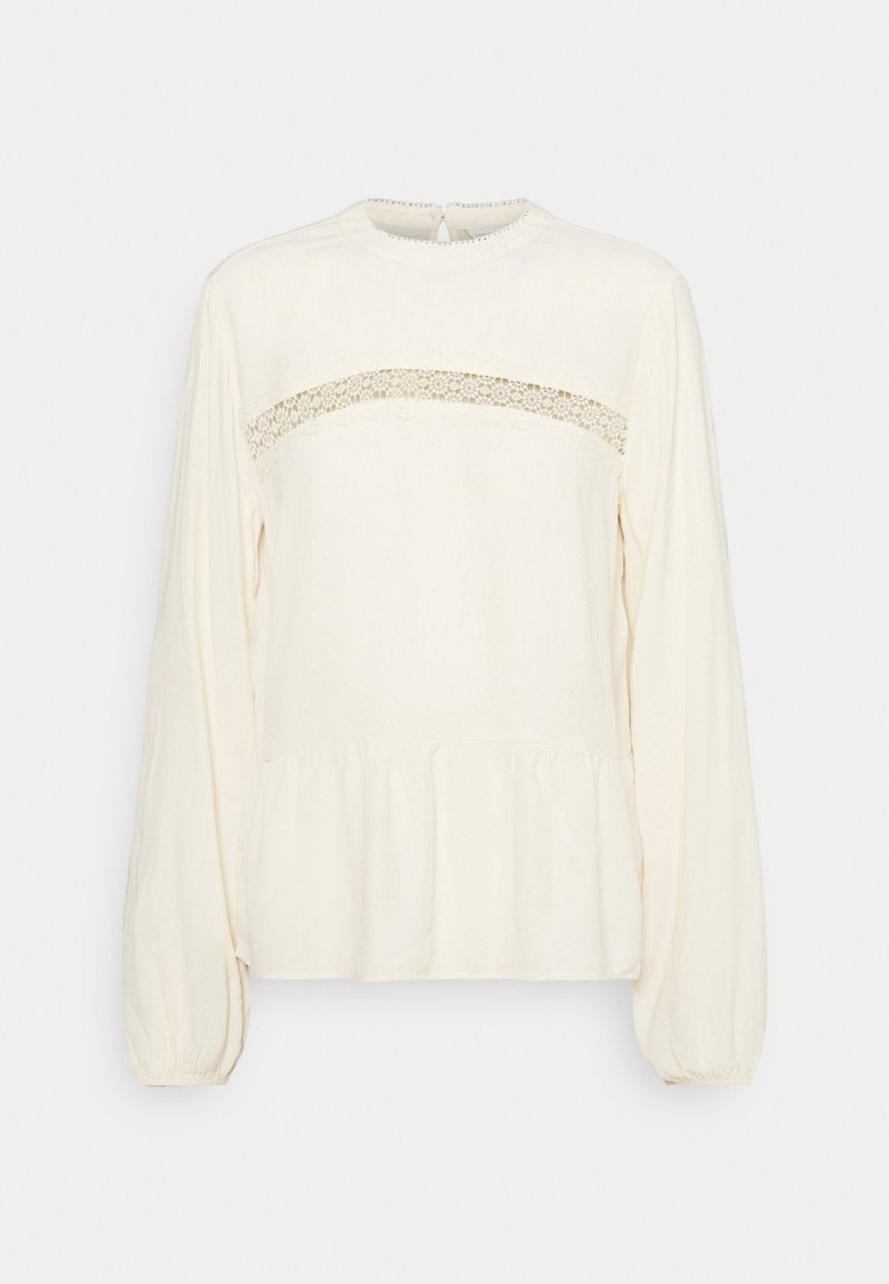 Krémová halenka s dlouhými rukávy a kulatým výstřihem, s krajkovým panelem přes hrudník a nařaseným peplum lemem. Měkká textura.