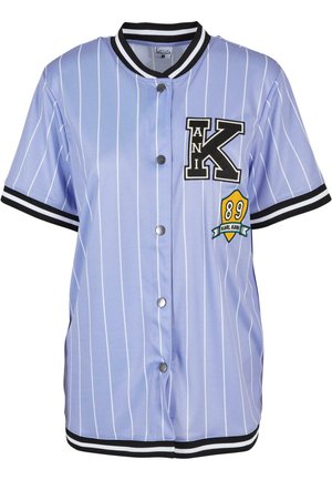 Lyseblå kortærmet trøje med hvide lodrette striber, sort krave og manchetter, prydet med et stort "K"-logo og et "89" emblem.