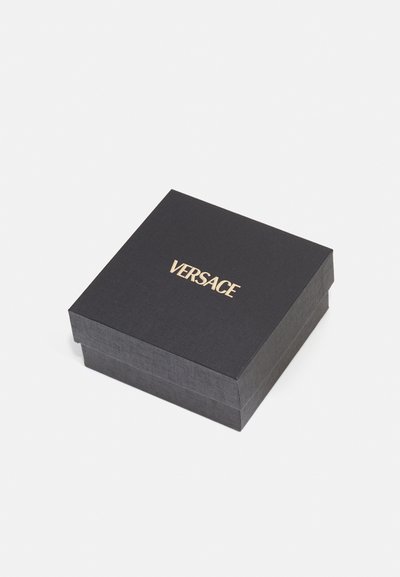 Cutie rectangulară neagră cu suprafață texturată, având un logo auriu "VERSACE" pe partea superioară, concepută pentru ambalare de lux.