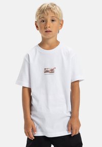 Camiseta de algodón blanca con un pequeño gráfico de una cámara retro en tonos apagados, mangas cortas, cuello redondo y un corte relajado.
