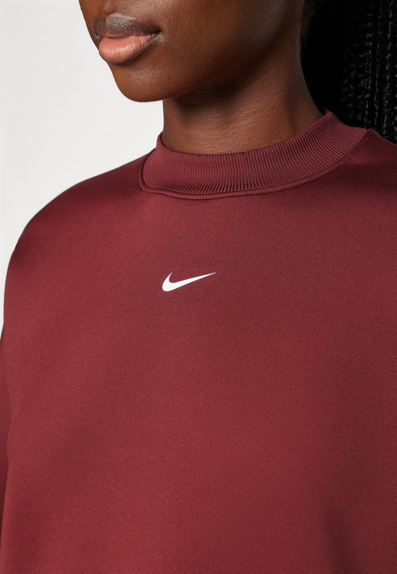 Felpa bordeaux con collo a barca a coste e piccolo logo bianco della Nike sul petto. Tessuto liscio, design minimalista.