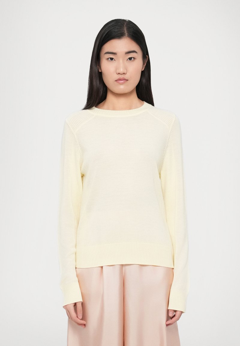 Ανοιχτό κίτρινο πλεκτό πουλόβερ με μακριά μανίκια, ριμπ μανσέτες και τελείωμα. Διαθέτει στρογγυλή λαιμόκοψη και υφασμάτινες λεπτομέρειες στους ώμους.