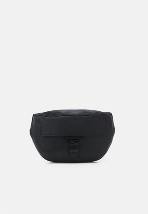 Sac bandoulière noir avec une finition douce et mate. Présente un rabat à l'avant et une fermeture à boucle. Forme arrondie avec un design minimaliste.