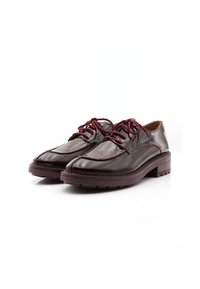 Chaussures en cuir marron avec une finition brillante, dotées de lacets bordeaux, d'une semelle épaisse et texturée, et de détails cousus le long des bords.